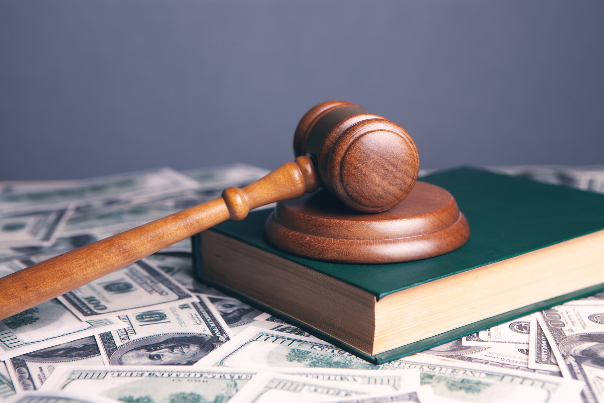 description: Image of a gavel, on top of a book, surrounded by money. Photo by Sasun Bughdaryan on Unsplash