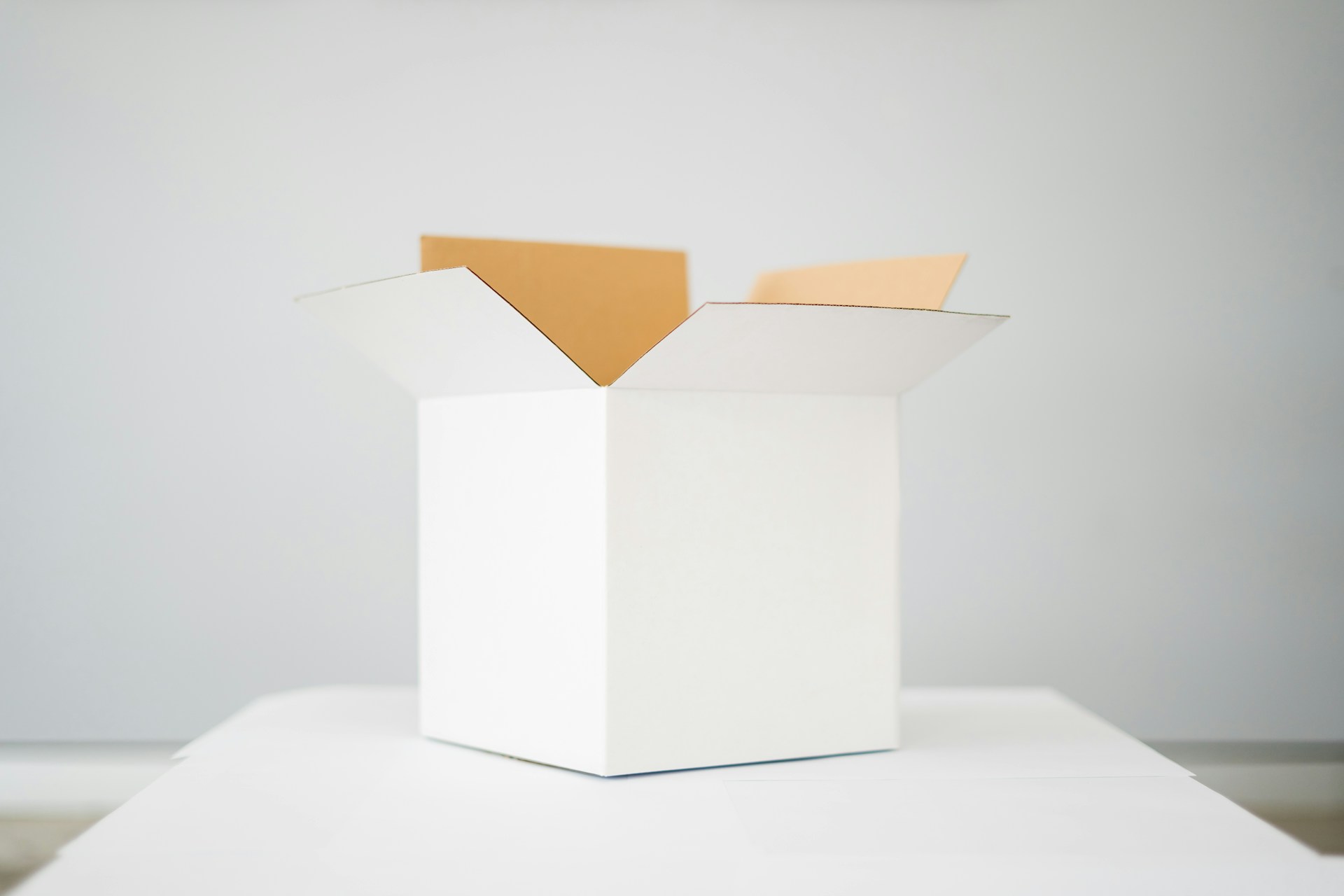 description: A white cardboard box, open, on a table. Photo by Kelli McClintock on Unsplash.